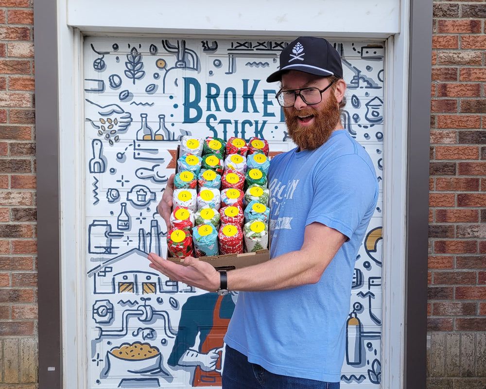 Brewer holding case of 24 hand wrapped beer cans.